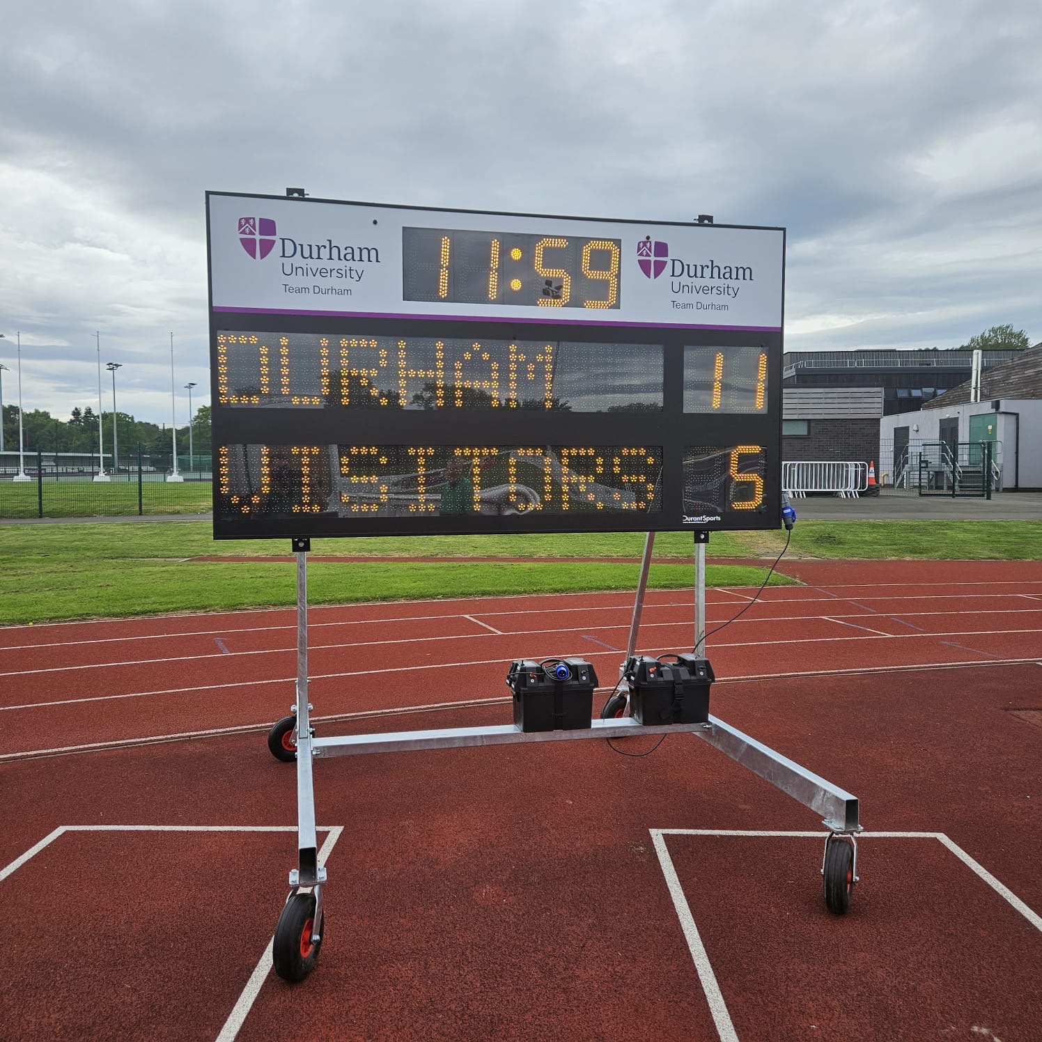 Mobile Durham University scoreboard beside an athletics track